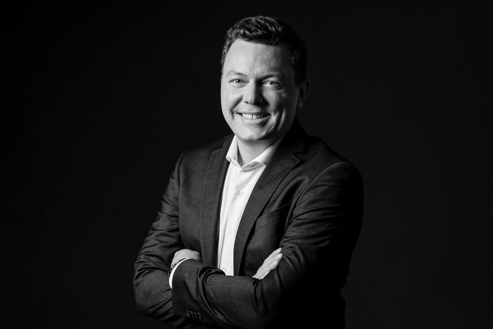 Schwarzweiß Portraitbild eines Mannes im Anzug vor einem schwarzen Hintergrund
